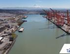 Aerial view of a port terminal with orange cranes over a waterway.
