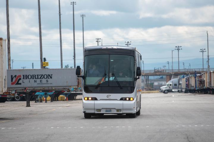 The front of a white and black bus in a parking lot. 