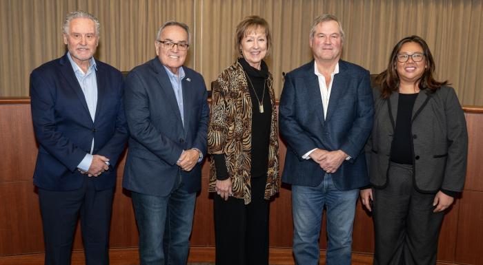 Group shot of three men and two women in front of a bench