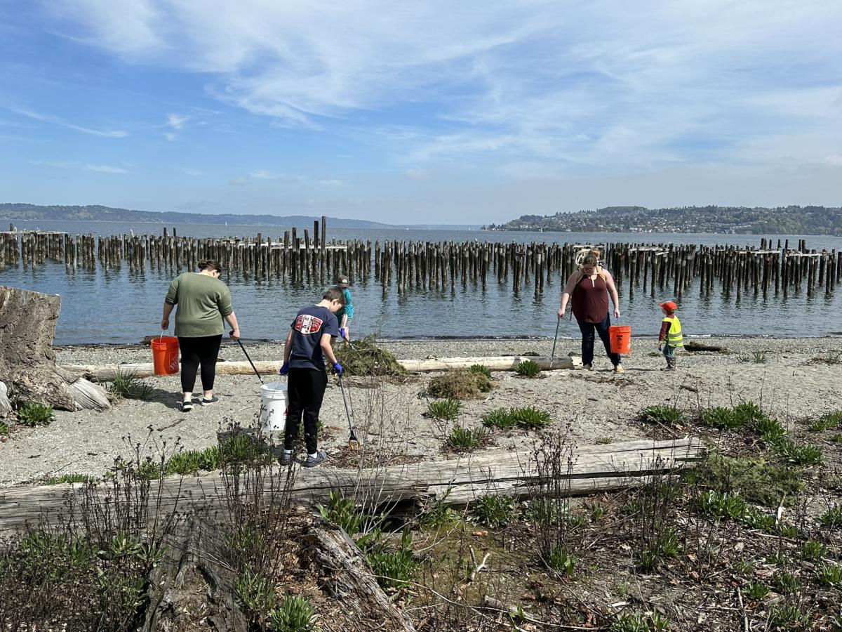 A group of people cleaning up trash on a beach.