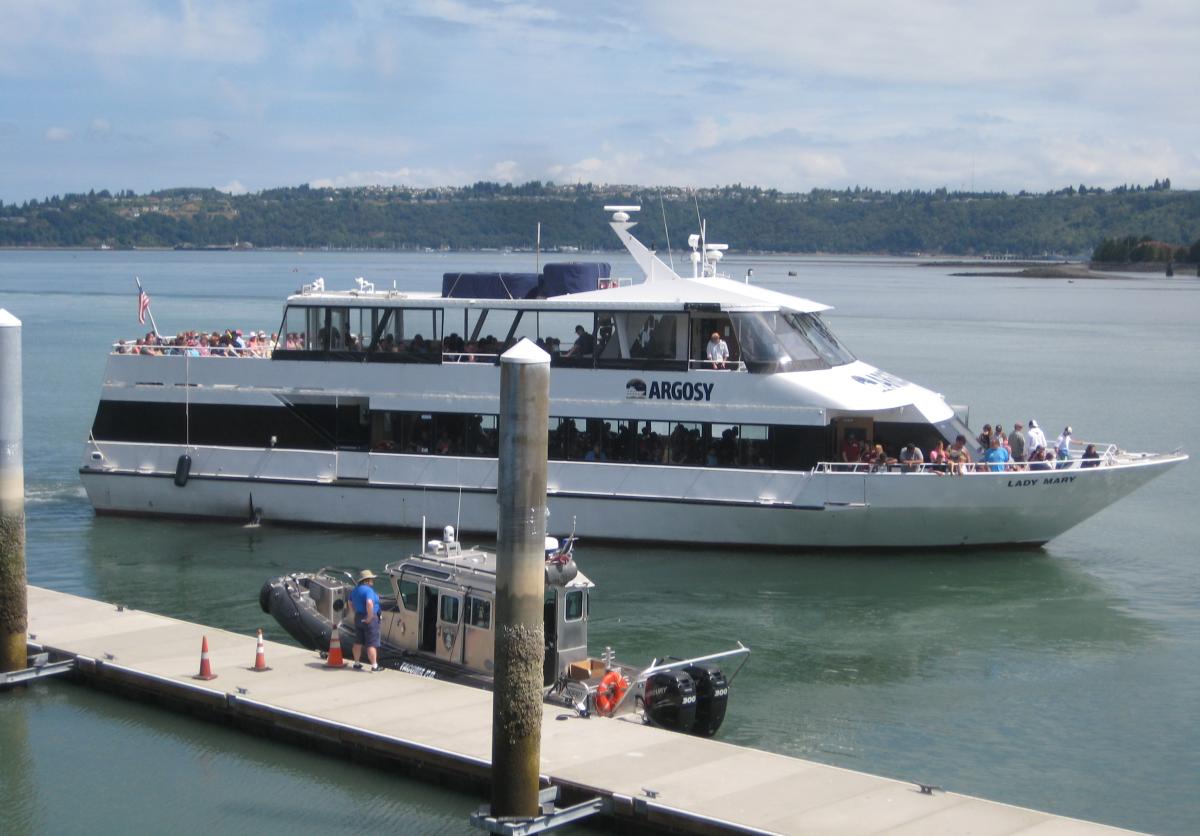 A small cruise ship pulling away from a dock. 