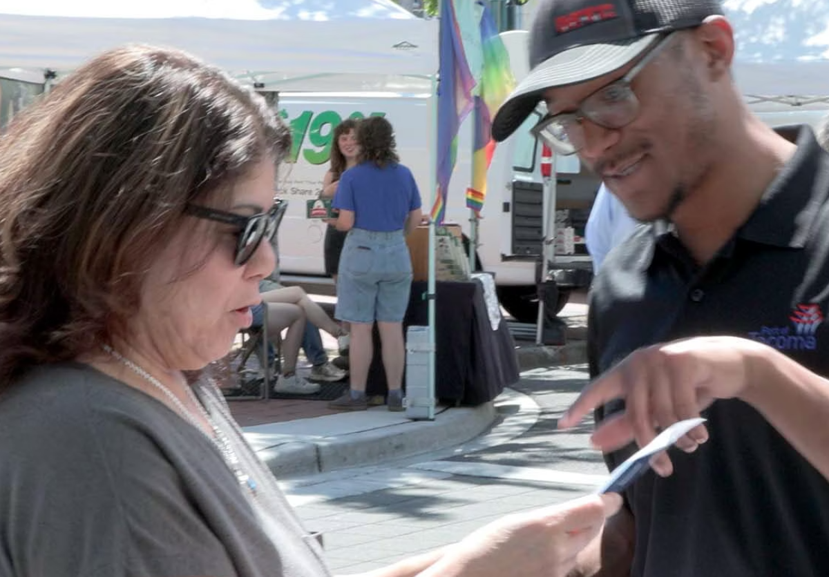 A man points at a piece of paper while speaking to a woman.