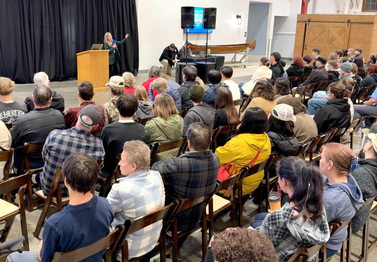 A group of people listen to a speaker talk at an event.