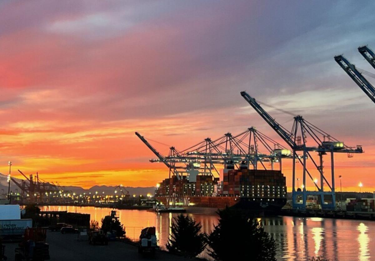 A Port of Tacoma terminal at sunset while a ship is loaded with cargo.