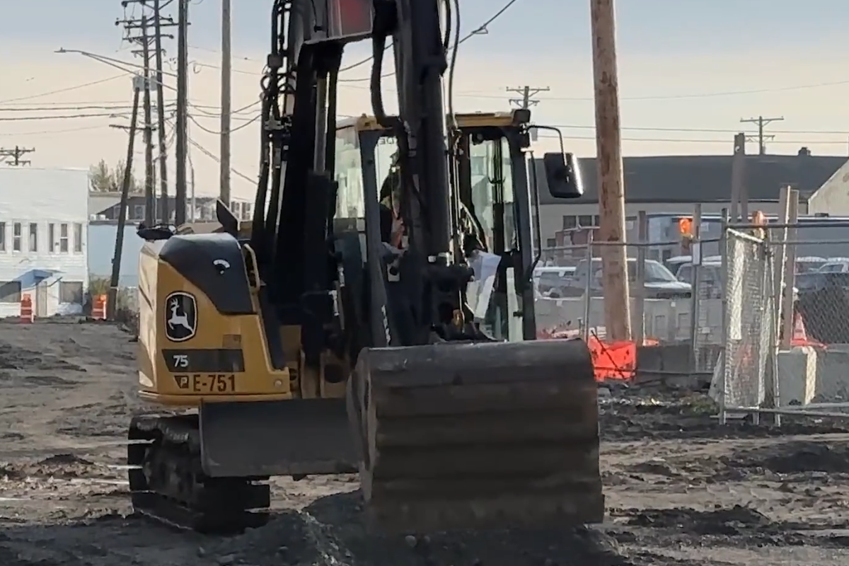 An excavator digs into dirt at a construction site.