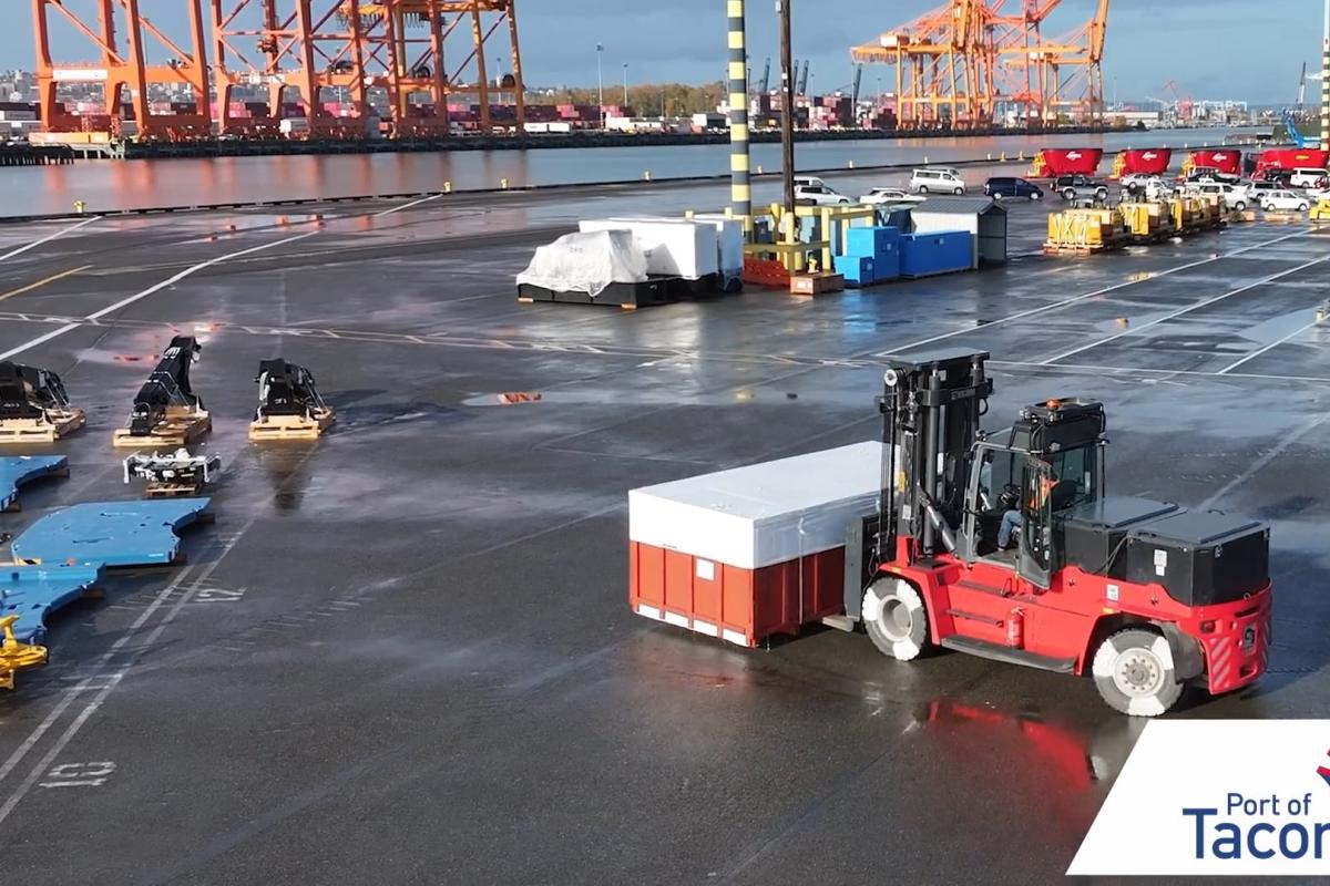 A red forklift moves a container through a port terminal.