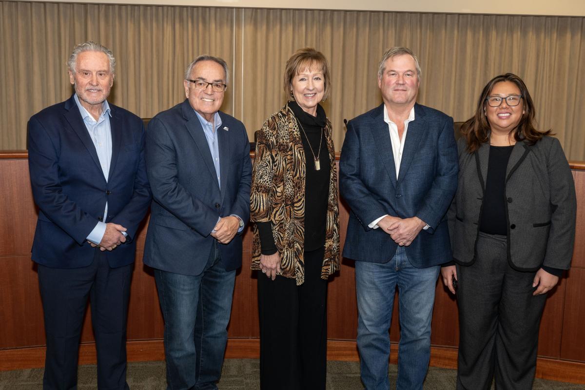 Group shot of three men and two women in front of a bench