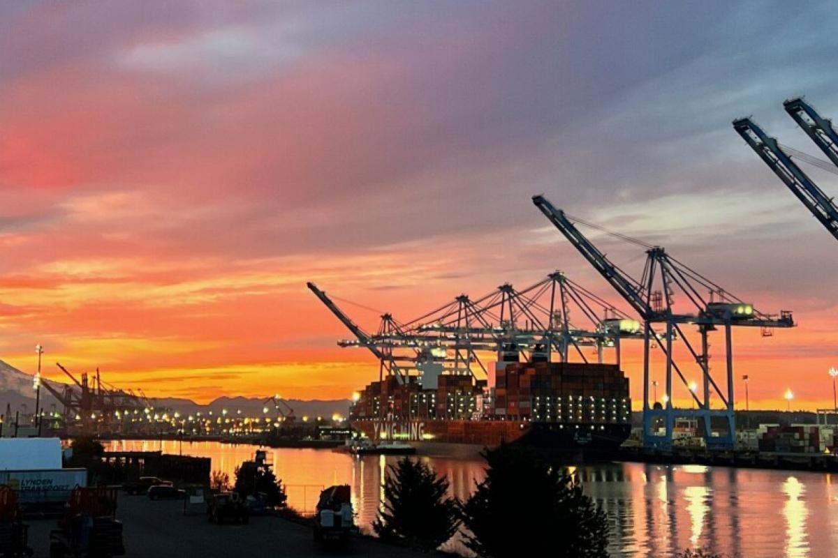 A Port of Tacoma terminal at sunset while a ship is loaded with cargo.
