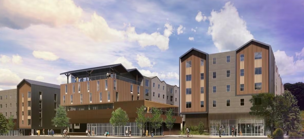 A modern multi-story building complex—Ashley at Yugo Flagstaff Central Flagstaff—features wood and metal facades, large windows, and ground-floor glass storefronts. Trees line the area as people stroll nearby under a partly cloudy sky.