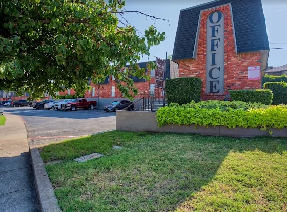 A building with a sign and a lawn, McCart Apartments Fort Worth offers comfortable living in a welcoming setting.