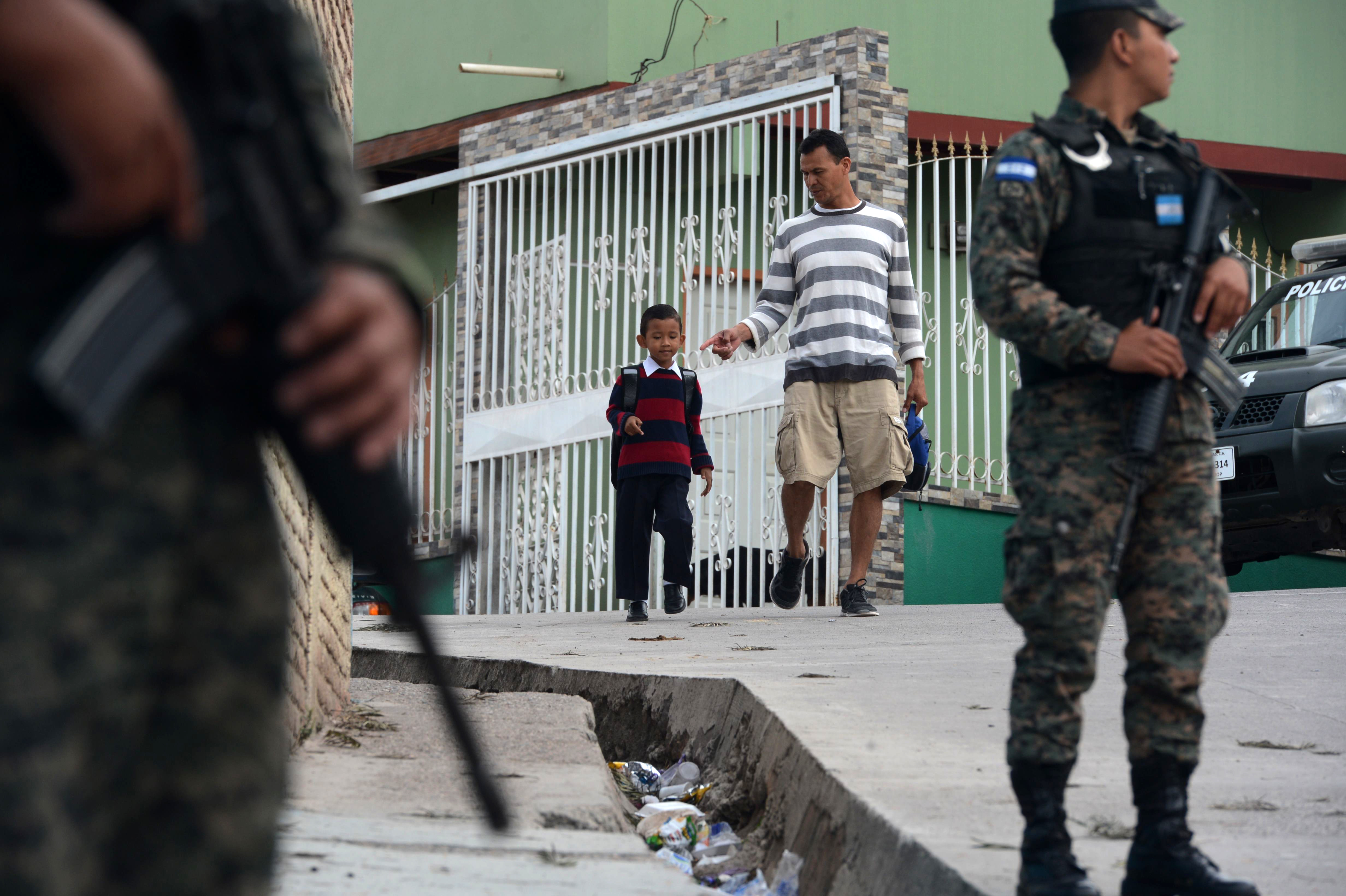 Miembros de la Policía Militar están de guardia cuando los estudiantes llegan a clase en la escuela Maximiliano Sagastume en Sagastume, Honduras. AFP