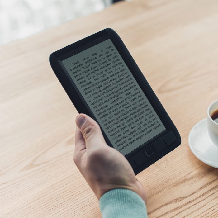 Pila de libros impresos y encuadernados junto a una taza de café sobre una mesa de madera.
