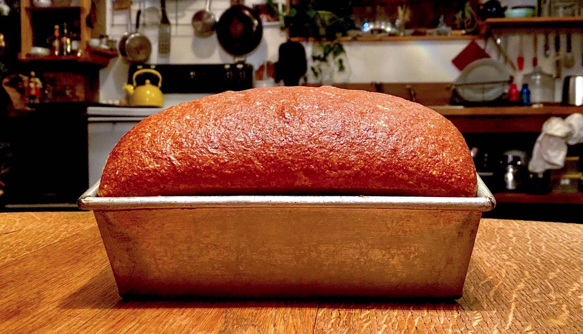 Loaf of bread in pan sitting on table in rustic kitchen