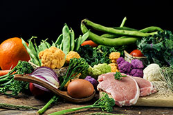 A pile of some fruit and some different raw vegetables