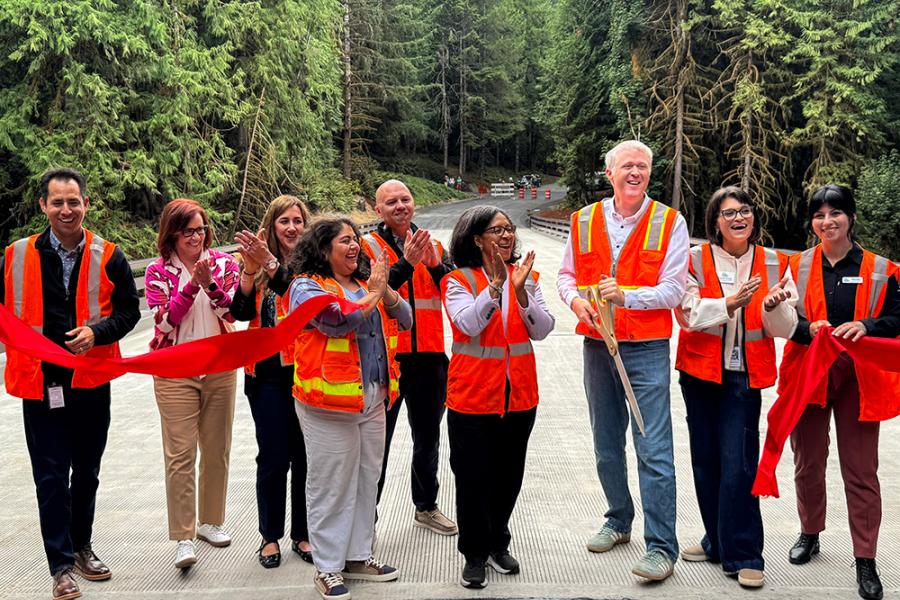 A group of officials applaud a ribbon cutting.