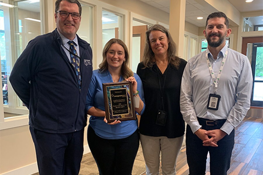 photo of four people receiving a thank you plaque