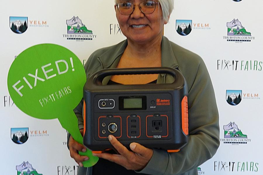 A person standing with a powerbank and a sign that says Fixed.