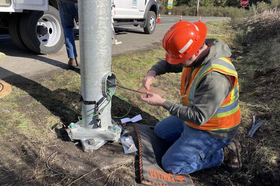 a Traffic Operations crew member reconnecting wire at the base of a street light
