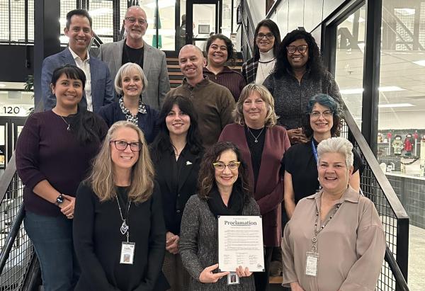 Board of Health members standing on stair case holding proclamation for national flu vaccination awareness week  