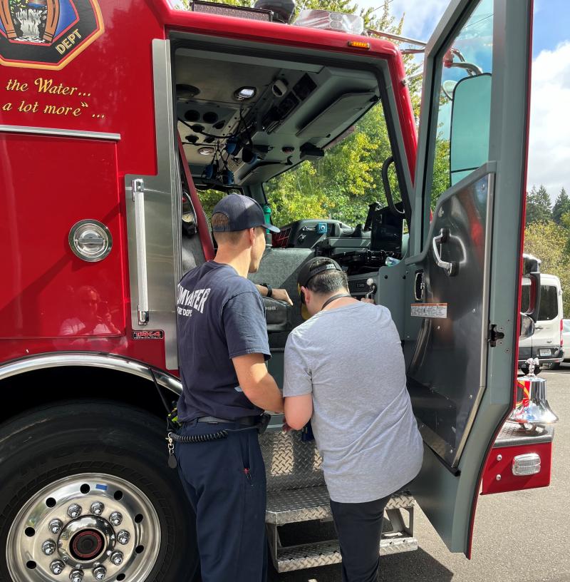 image of male fire fighter helping individual into fire truck 