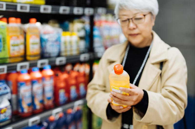 Close up of senior woman shopping for household cleaner in supermarket