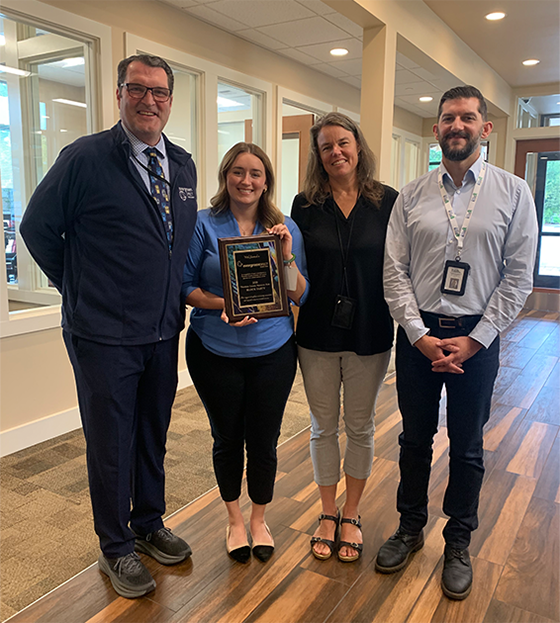 photo of four people receiving a thank you plaque