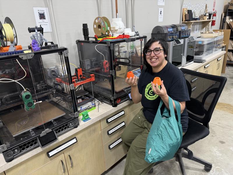 Photo of a young person showing off 3D printed parts.