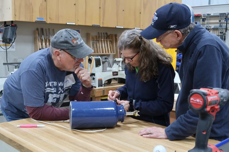 3 adults working on fixing a lamp.