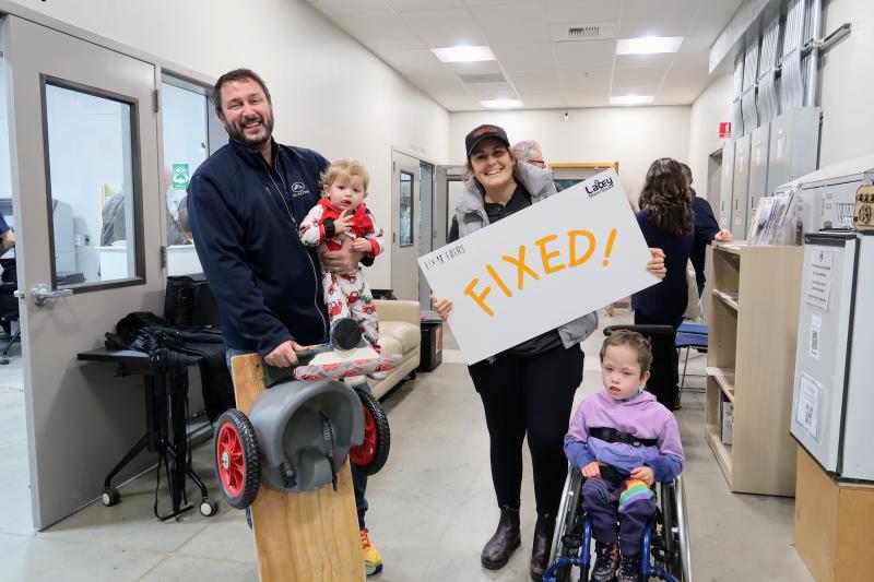 a family holding their son's chair and a "Fixed!" sign