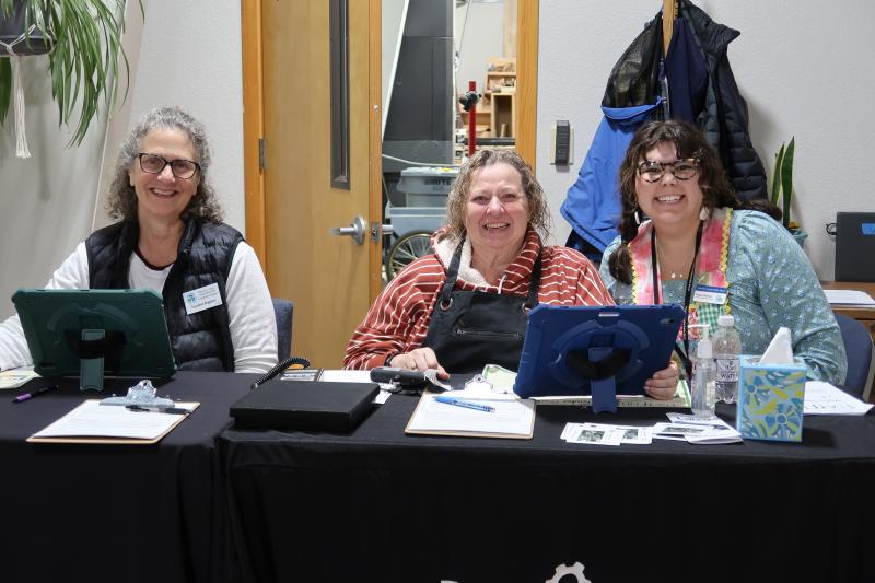 3 adults welcoming people to the Fix-It Fair.