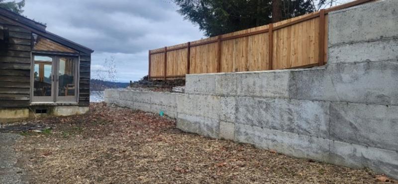 A concreate wall with wood fencing on top of it along the shoreline