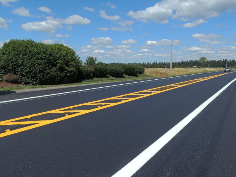 a freshly painted road featured with a blue sky, dotted with clouds