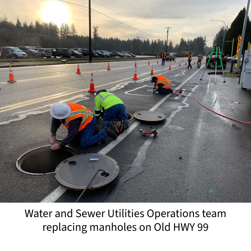 Water and Sewer Utilities Operators replacing manhole covers on Old HWY 99. Workers shown in utility high-vis vests and safety gear, removing parts of manhole cover from roadway