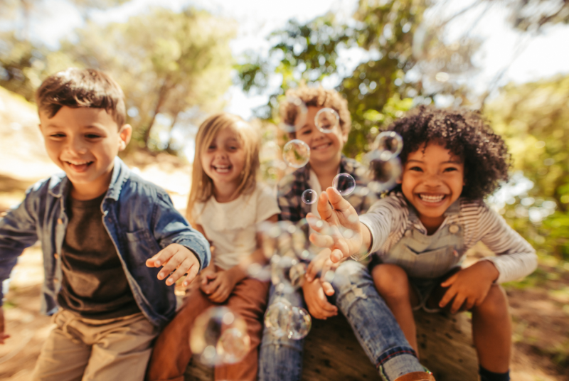 four children smiling and playing with bubbles 