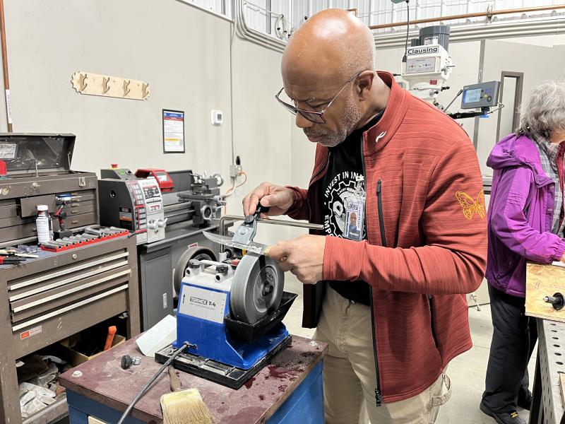 A man uses tools to sharpen a knife.