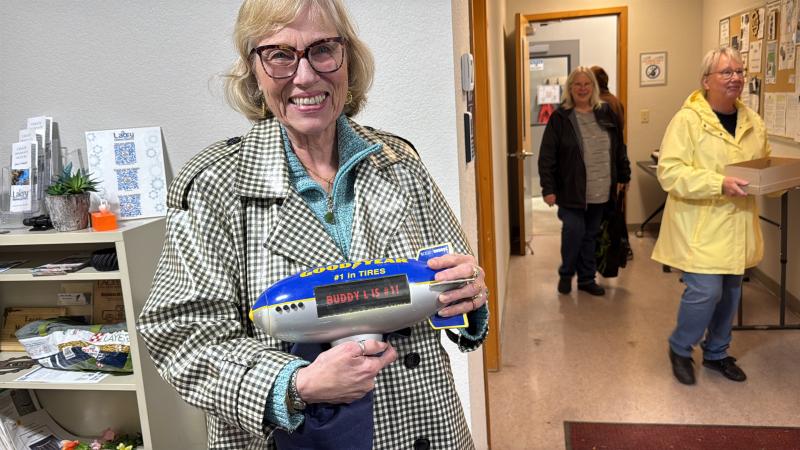 A woman poses with a repaired toy blimp.