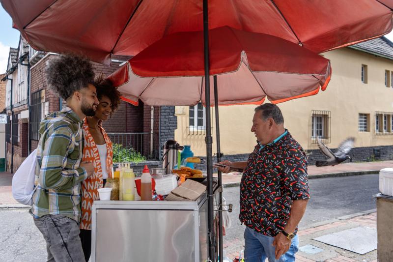 Young friends buying arepas on the city streets from a street vendor.