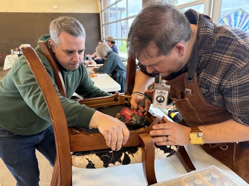 Two men repair a broken chair.