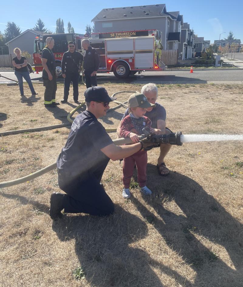 photo of project safer team member using fire hose with firefighter
