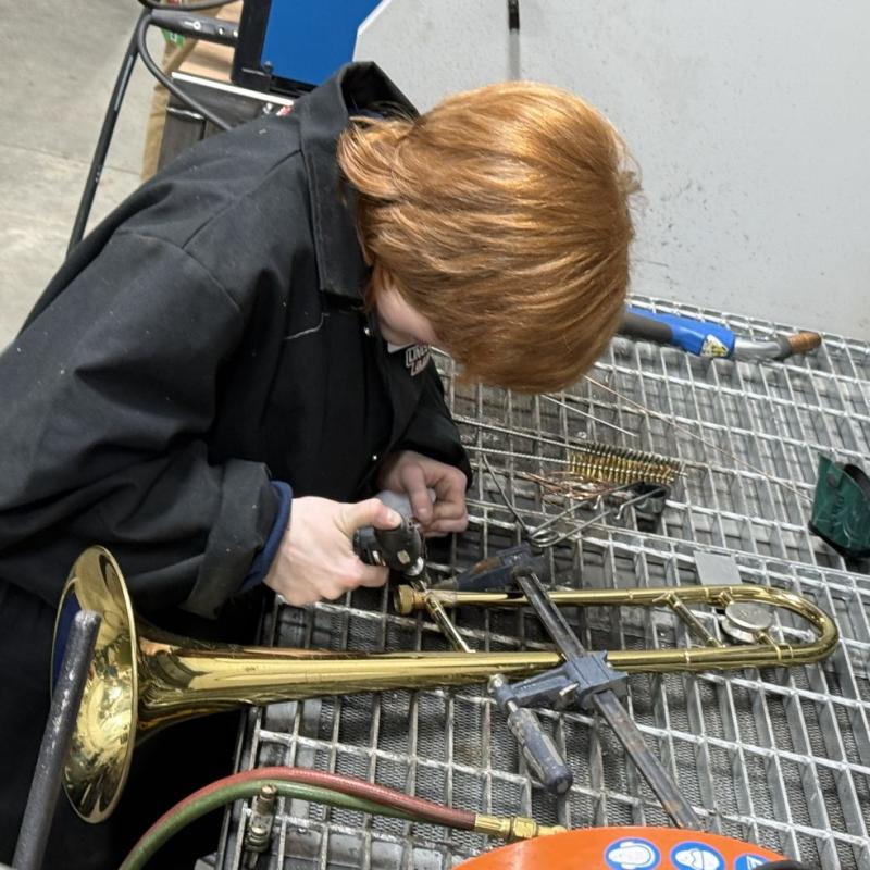 A woman repairs a broken trombone.