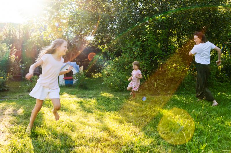 Happy family enjoying playful outdoor time running in the sunny backyard