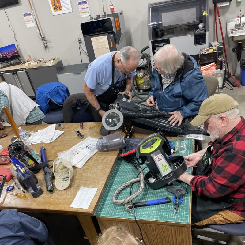 Volunteers repair broken vacuum cleaners.