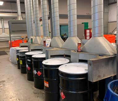 The image shows a line of industrial drums equipped with dedicated Local Exhaust Ventilation (LEV) hoods and ducting to capture airborne contaminants directly at the source.