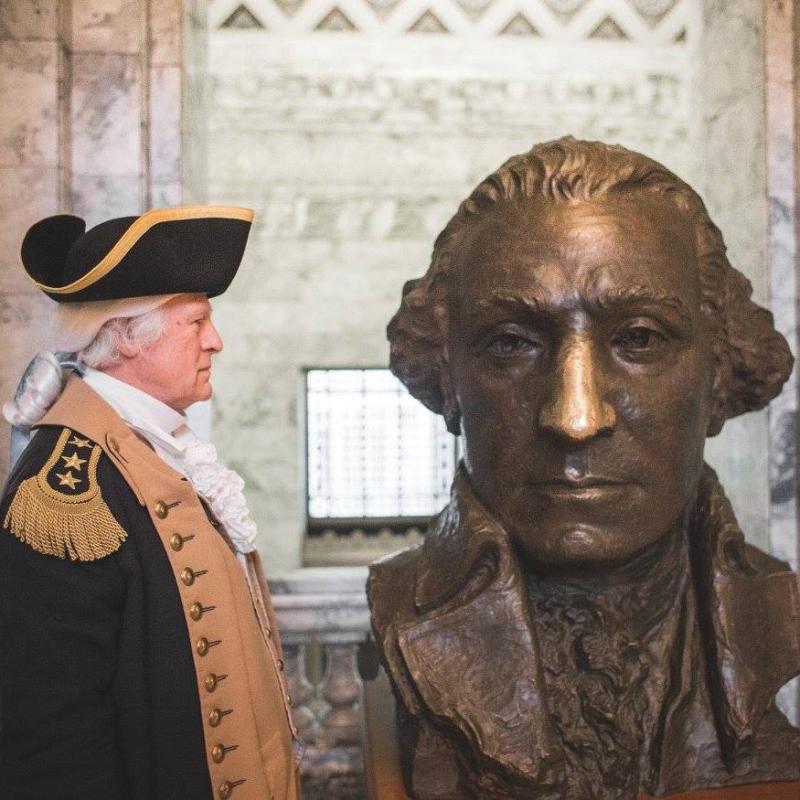 Vern Frykholm shown dressed as George Washington with a brass bust of George Washington