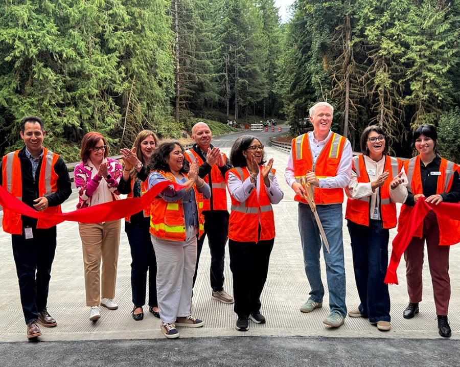 A group of officials applaud a ribbon cutting.