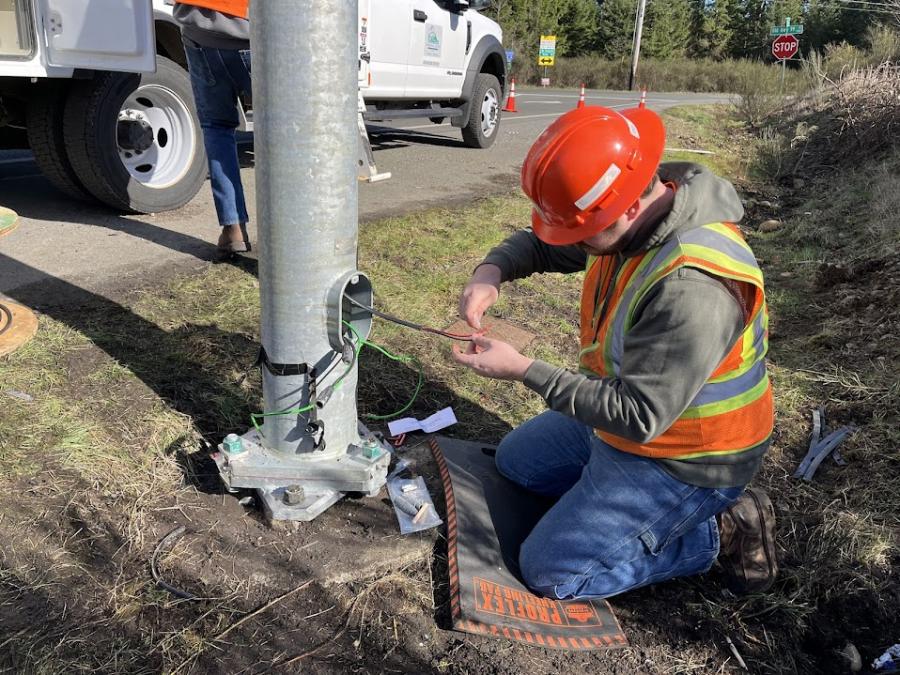 a Traffic Operations crew member reconnecting wire at the base of a street light