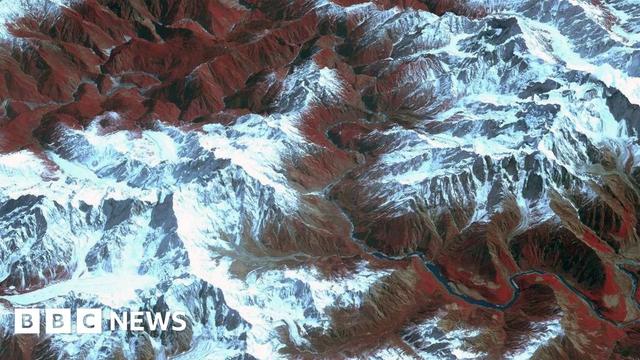 A satellite image showing the Yarlung Tsangpo canyon, with steep snow-covered peaks of mountains surrounding the river