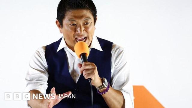 選挙活動最終日の7月19日、オレンジ色のマイクを持った参政党の神谷宗幣党首が党旗の前で支持者に語りかけている
