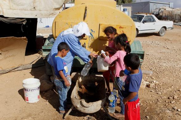 Palestinians fill plastic bottles and jerry cans with drinking water from a water tank in the West Bank village of Um al-Khair south of Hebron, August 17, 2016. (Photo: Wisam Hashlamoun/APA Images)