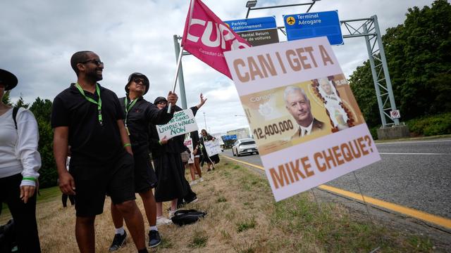 A sign with a photo of Air Canada CEO Michael Rousseau on it is seen as striking Air Canada flight attendants rally at Vancouver International Airport, in Richmond, British Columbia, Monday, Aug. 18, 2025. (/Darryl Dyck/The Canadian Press via AP)